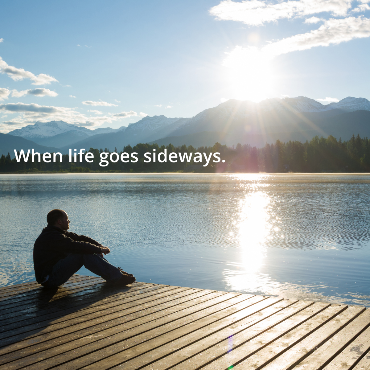Person sitting on a dock overlooking a calm lake and mountains, reflecting during a life transition